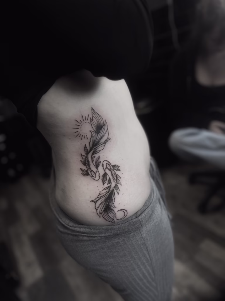 Fresh koi fish tattoo on Nieve’s ribs, created at The Viper Pit Tattoo Studio in Manchester during a summer heatwave, bold black outlines with vibrant colour detail.