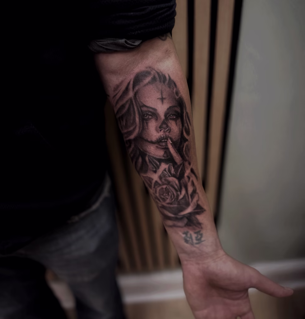 Black and grey Day of the Dead girl tattoo with detailed shading, rose, and “shh” finger pose, done at The Viper Pit Tattoo Studio in Irlam, Manchester.