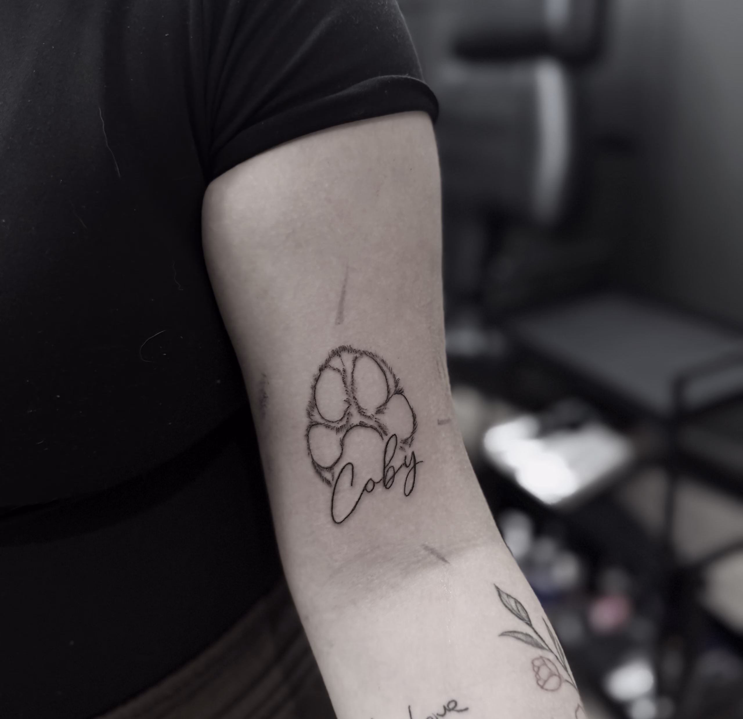 Turning Your Pet’s Paw Print into a Tattoo: An Irlam Planning Guide 1 Fine-line paw print tattoo with the name Coby on an upper arm, by Chris at The Viper Pit in Irlam
